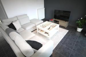 a living room with a white couch and a tv at Duplex Brussels airport 2 Chambre in Wezembeek-Oppem