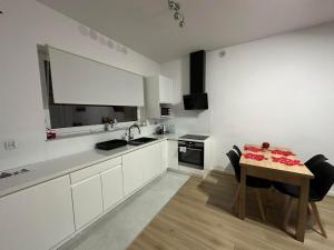 a white kitchen with a table and a sink at Apartament ANNA in Biała Podlaska