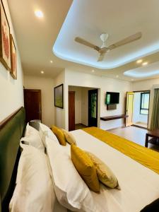 a bedroom with a large white bed with yellow pillows at Tea & Sky Munnar in Munnar +32 photos