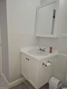 a white bathroom with a sink and a mirror at The Cherryhill of Old Harbor in Old Harbour