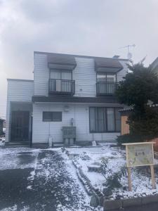 a house with snow on the ground in front of it at やすらぎの宿 菜の香 in Biei