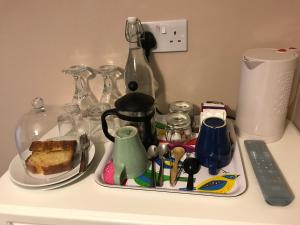 a tray with a tea kettle and a plate with a piece of cake at Number 29 - Only Adults in Shanklin