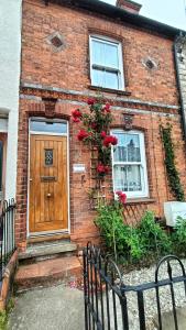 uma casa de tijolos com uma porta de madeira e rosas vermelhas em CNTRL Reading Modernized 3 bedroom House em Reading