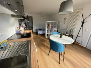 uma cozinha e sala de estar com uma mesa branca e cadeiras azuis em Escapade Ticino em Neggio