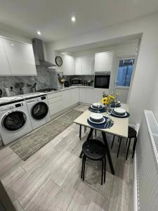 a kitchen with a table and washing machines at Modern 5 Bed near ExCel -Big Ben in London