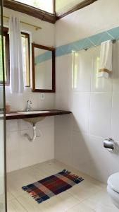 ein Bad mit einem Waschbecken und einem Spiegel in der Unterkunft Chalé Sabiá in Aiuruoca