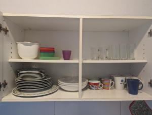 un armario lleno de platos y tazas y tazones en FeWo Hafen: Apartment in a Great Location, en Dortmund