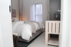 a white bedroom with a bed and a window at Urbane- By LaSerene -Carlswald in Midrand