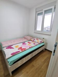 a small bed in a room with a window at Stan na dan M in Novi Sad