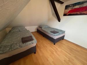 two beds in a small room with wooden floors at Pension Hotel Leinefelde am Bahnhof in Leinefelde +10 photos