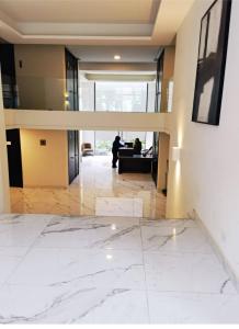 a lobby with white marble flooring and a person in a living room at Hermoso Lofts Centro De Santiago in Santiago