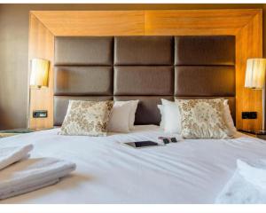 a bedroom with a large white bed with a large headboard at Chambre Hôtel Ibiza Spa - Hammam - Jacuzzis - Piscine Chauffée in Les Deux Alpes