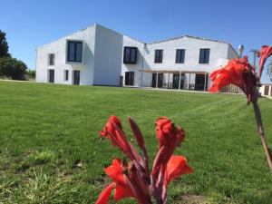 uma grande casa branca com flores vermelhas no quintal em MAS CATXINA Hotel Boutique 4 estrellas em Deltebre