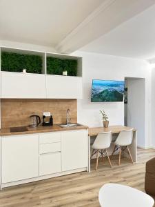 a kitchen with white cabinets and a table and chairs at Under Castle Apartment in Ljubljana