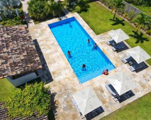 an overhead view of people in a swimming pool with umbrellas at Pousada Villages Boutique Hotel - 150m da Praia da Laje in Pôrto de Pedras