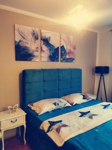 a bedroom with a blue bed with three pictures on the wall at City Center Apartment JOTIC in Pirot