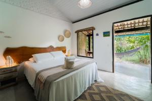 a bedroom with a bed and a large window at Pousada Caraiva Guest House in Caraíva