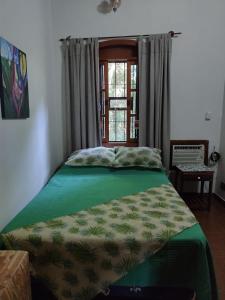 a bedroom with a green bed with a window at Quinta La calmita Iguazú in Puerto Iguazú