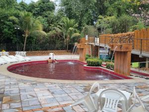 a pool with a fountain with white chairs around it at Flat 317 Golden Dolphin Express in Caldas Novas