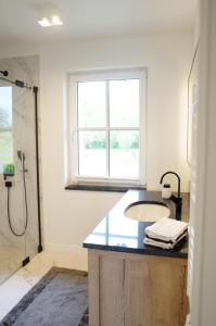 a bathroom with a sink and a shower with a window at Ferienwohnung Feldblick in Sehlen