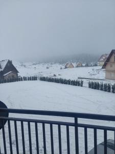 einen schneebedeckten Hof mit Häusern und einem Zaun in der Unterkunft Apartman Tea in Kupres