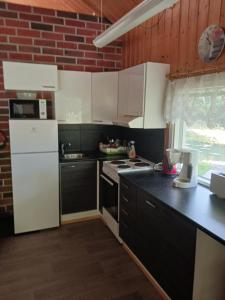 cocina con electrodomésticos blancos y encimera negra en Perälampi, en Huissi