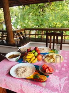 阿勒皮的住宿－'Marari Johns Homestay' Mararikulam, Alappuzha，一张桌子,上面有盘子,放在粉红色的桌布上