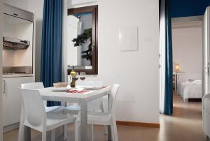 Hotel Villa Sveva في كالياري: طاولة غرفة طعام بيضاء مع كراسي بيضاء ومرآة