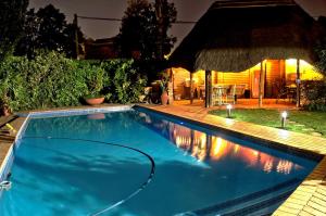 a swimming pool in front of a house at night at Rest-a-While Guest House - Pretoria in Pretoria