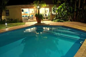a swimming pool in a yard at night at Rest-a-While Guest House - Pretoria in Pretoria