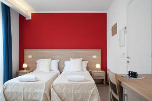 two beds in a room with a red wall at Hotel Villa Sveva in Cagliari