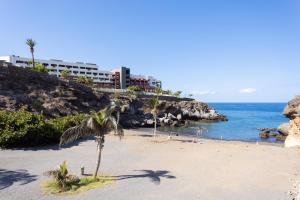 a beach with palm trees and a hotel in the background at Ocean View Paradise 1116 in Adeje