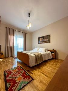 una camera con un letto e un tappeto su un pavimento in legno di Villa Malo Guesthouse a Korçë