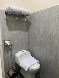 a small bathroom with a white toilet and towels at Genio Syariah Hotel Solo in Tjolomadu