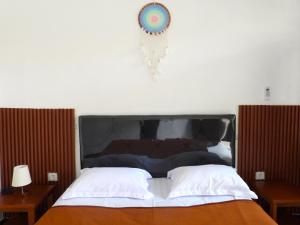 un lit avec une tête de lit noire, 2 tables et une horloge dans l'établissement Pondok Dete Guesthouse, à anur