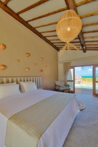 a bedroom with a large white bed and a chandelier at MONAN BOUTIQUE HOTEL in Pôrto de Pedras