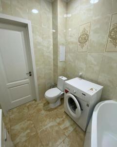 a bathroom with a toilet and a washing machine at APARTAMENT в мкр Батыс-2 в комфортном ЖК Нектар in Aktobe