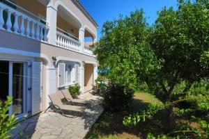 uma casa branca com uma árvore e um banco em Spiros Saint Stephanos em Ágios Stéfanos