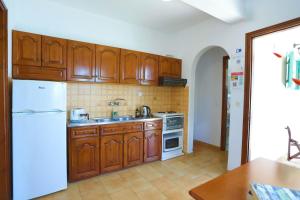 a kitchen with wooden cabinets and a white refrigerator at Spiros Saint Stephanos in Ágios Stéfanos