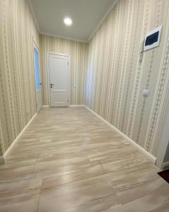an empty room with a door and wooden floors at APARTAMENT в мкр Батыс-2 в комфортном ЖК Нектар in Aktobe