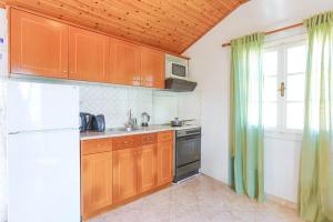 a kitchen with wooden cabinets and a white refrigerator at Anna Apartment Agios Stephanos in Ágios Stéfanos