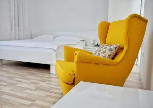 a yellow chair and a bed in a room at Apartments Barbati in Novalja