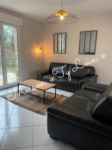 sala de estar con sofá de cuero negro y mesa en Villa Ty Loin vue mer 8 personnes, en Logonna-Daoulas