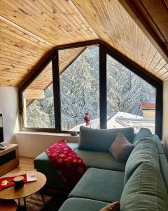 a living room with a green couch and a large window at Pamporovo Rhodopi Pearl Apartments - Private Apartments in Pamporovo