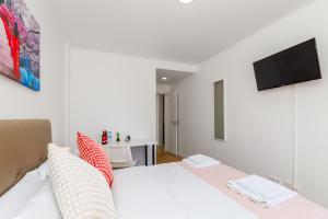 a bedroom with a white bed and a flat screen tv at Mia Guest House in Setúbal