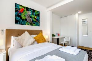 a bedroom with a bed with a painting on the wall at Mia Guest House in Setúbal