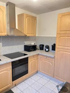 a kitchen with wooden cabinets and a black microwave at CICONIA : CENTRE-VILLE MULHOUSE, PARC NOUVEAUX BASSINS A PROXIMITE in Mulhouse +5 photos