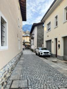 un'auto parcheggiata su una strada di ciottoli tra gli edifici di Al Teatro Romano - CIR 0343 ad Aosta