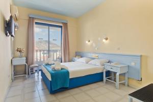 a bedroom with a large bed and a window at Regina Studios & Hotel in Karpathos