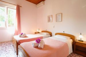 Dos camas en una habitación de hotel con flores. en Irena Saint Stephanos, en Ágios Stéfanos